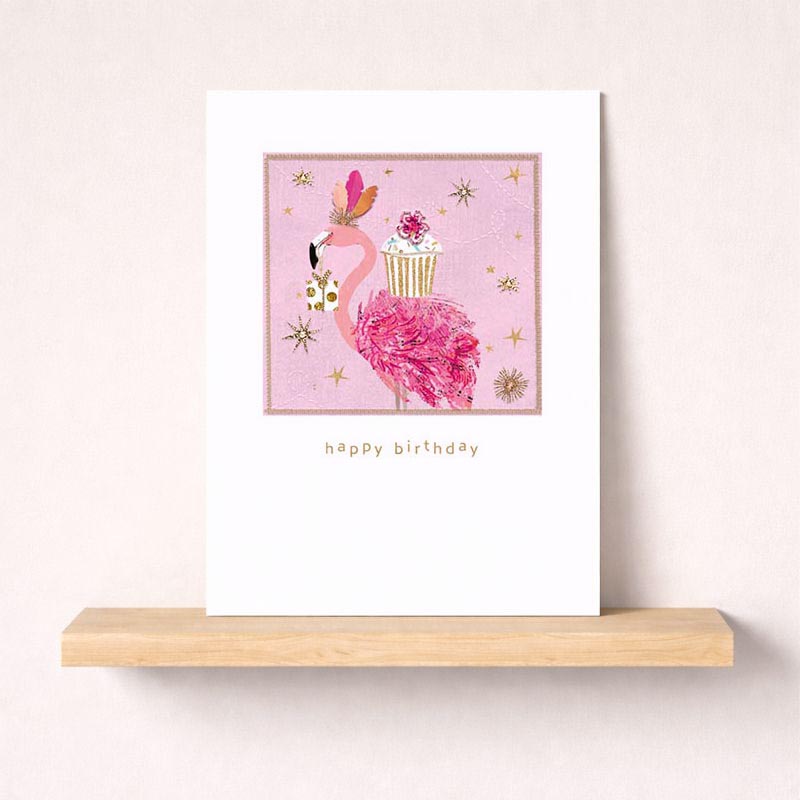 Adorable pink flamingo greetings card with cupcake under starlit sky. Perfect for birthdays and celebrations. Spread joy with this cute design.