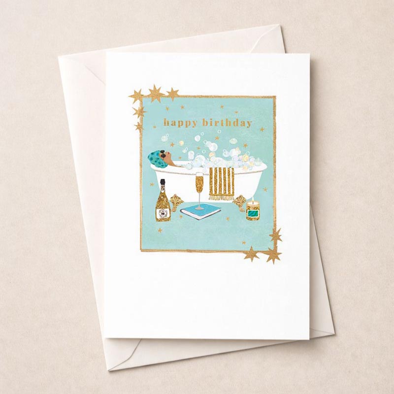 Luxurious bathtub with bubbles, champagne, and crown-topped liquor bottle on greetings card. Perfect for a special birthday celebration.