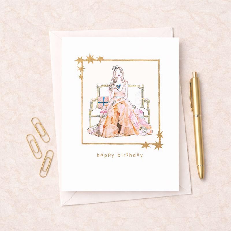 Charming birthday greetings card with woman on bed, pastel colours, "Happy Birthday" message. Perfect for showing you care.