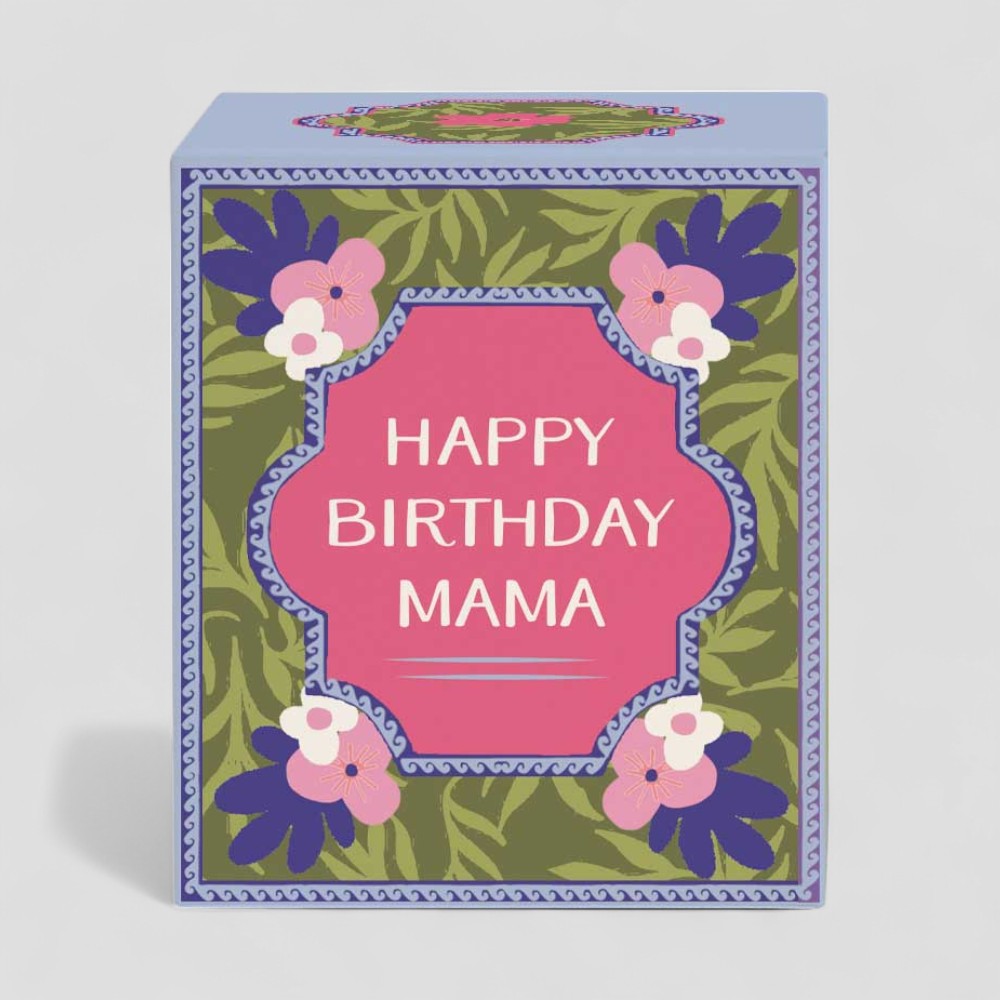 Lit yellow candle with happy birthday mama label next to matching decorative box