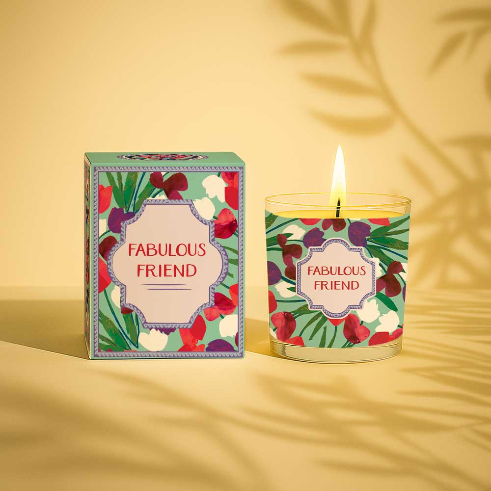 Lit yellow candle in glass with floral design and Fabulous Friend gift box.