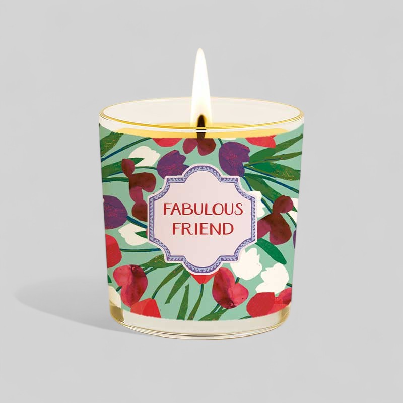 Lit yellow candle in glass with floral design and Fabulous Friend gift box.