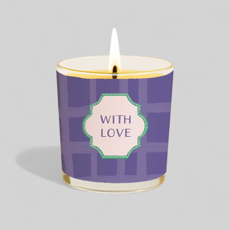 Lit yellow candle in glass with purple box labelled with love