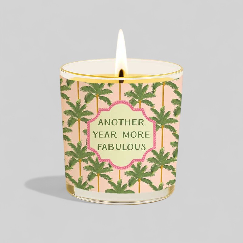 Lit yellow candle with tropical design and box saying Another year more fabulous