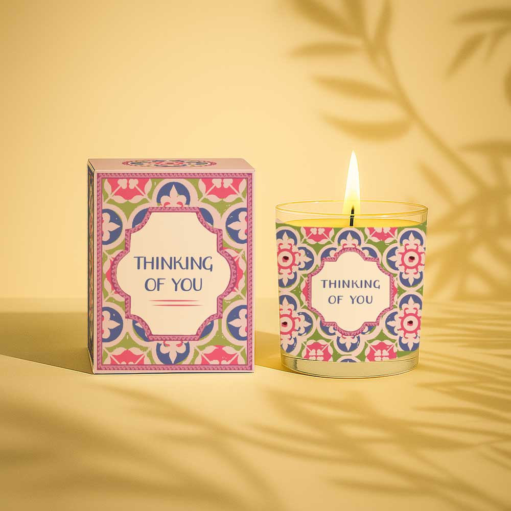 Lit yellow candle with thinking of you label next to matching decorative box