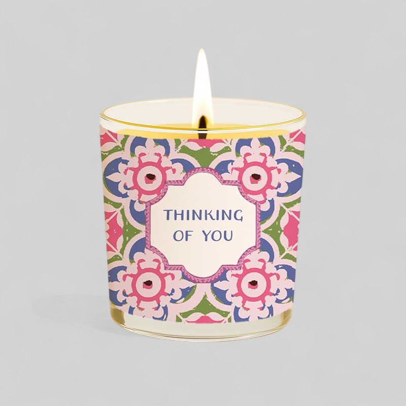 Lit yellow candle with thinking of you label next to matching decorative box