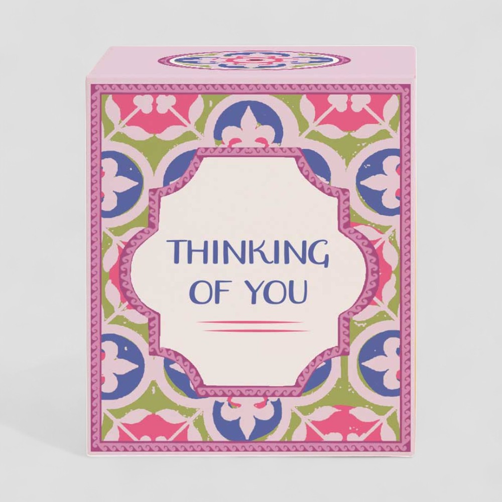 Lit yellow candle with thinking of you label next to matching decorative box