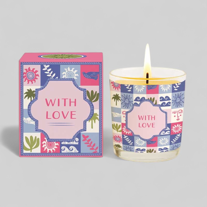Lit yellow candle in glass with colourful patterned box labelled with love