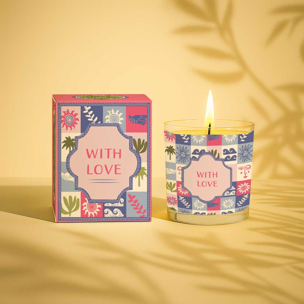 Lit yellow candle in glass with colourful patterned box labelled with love
