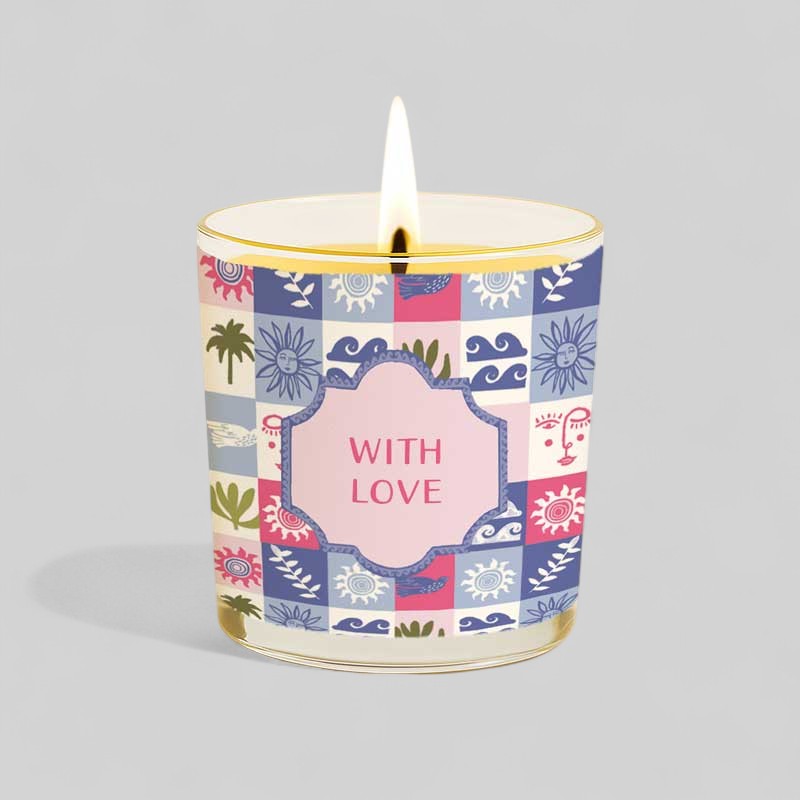 Lit yellow candle in glass with colourful patterned box labelled with love
