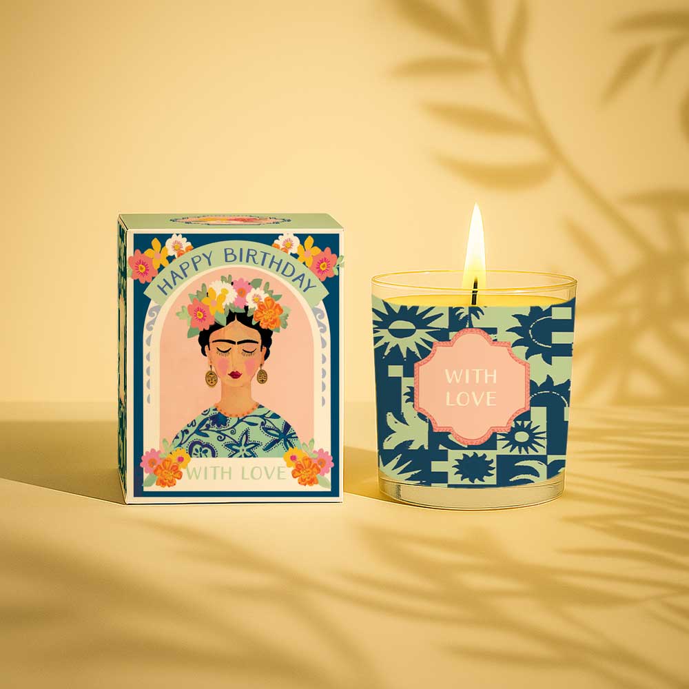 Lit yellow candle in glass next to happy birthday with love decorative box