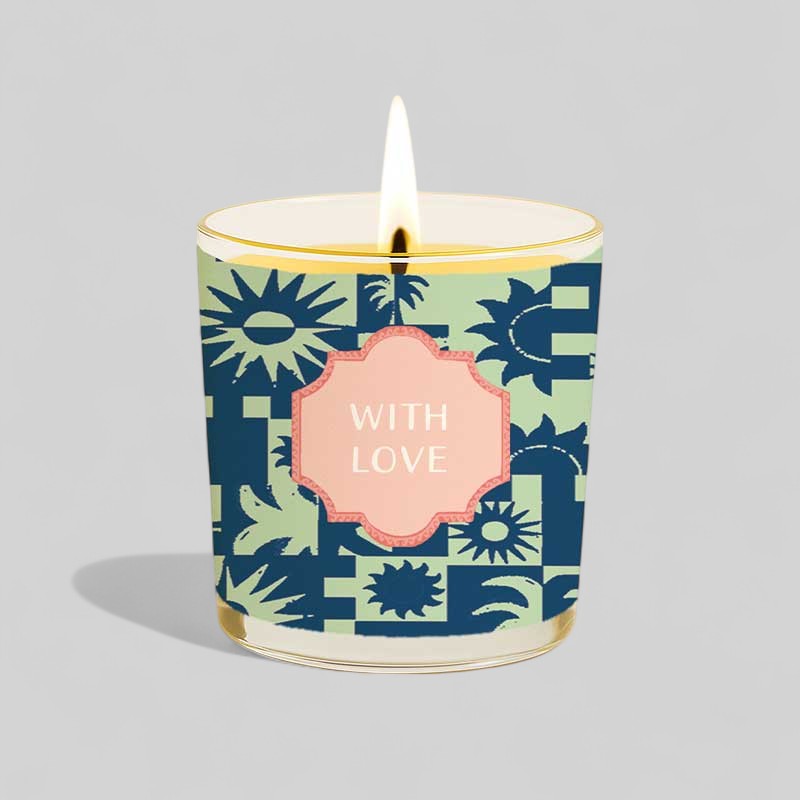 Lit yellow candle in glass next to happy birthday with love decorative box