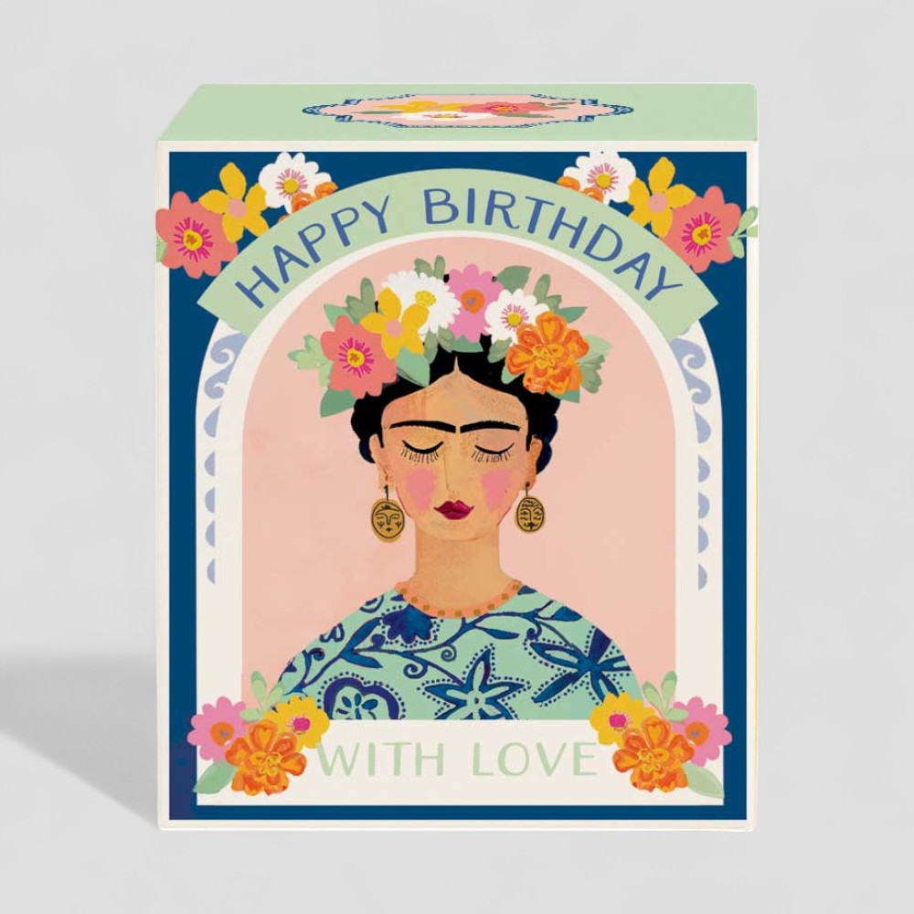 Lit yellow candle in glass next to happy birthday with love decorative box