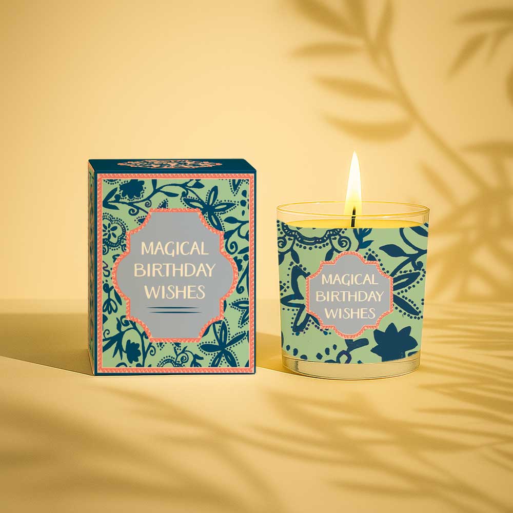 Burning yellow candle in glass with magical birthday wishes box and label