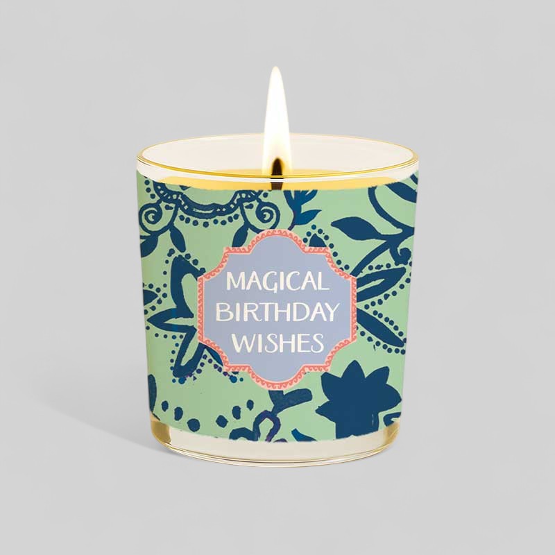 Burning yellow candle in glass with magical birthday wishes box and label