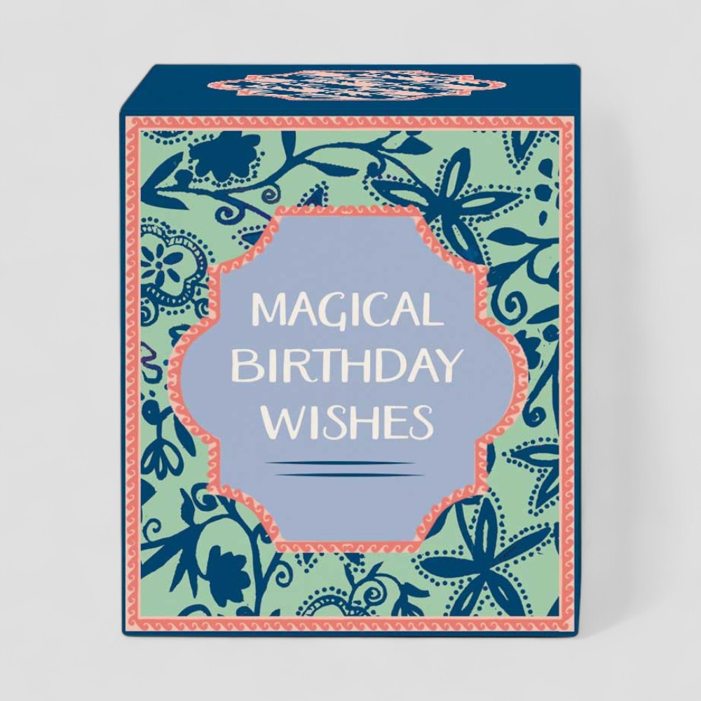 Burning yellow candle in glass with magical birthday wishes box and label