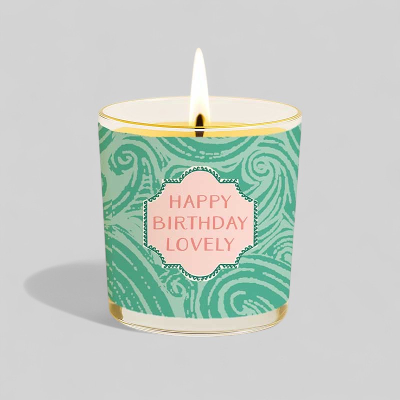 Lit yellow candle in glass with happy birthday lovely message and matching gift box