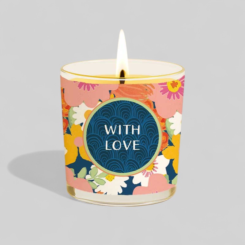 Lit yellow candle in glass with floral happy birthday gift box