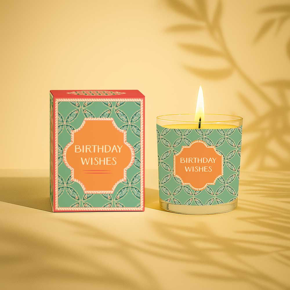 Lit yellow candle in glass with birthday wishes packaging and label