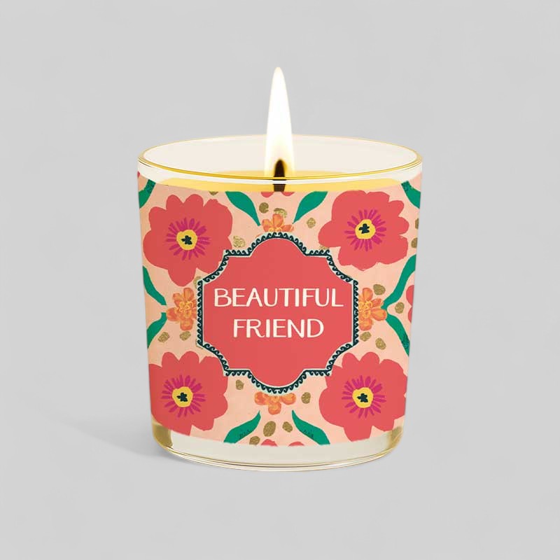 Lit yellow candle in glass with floral patterned beautiful friend box and label