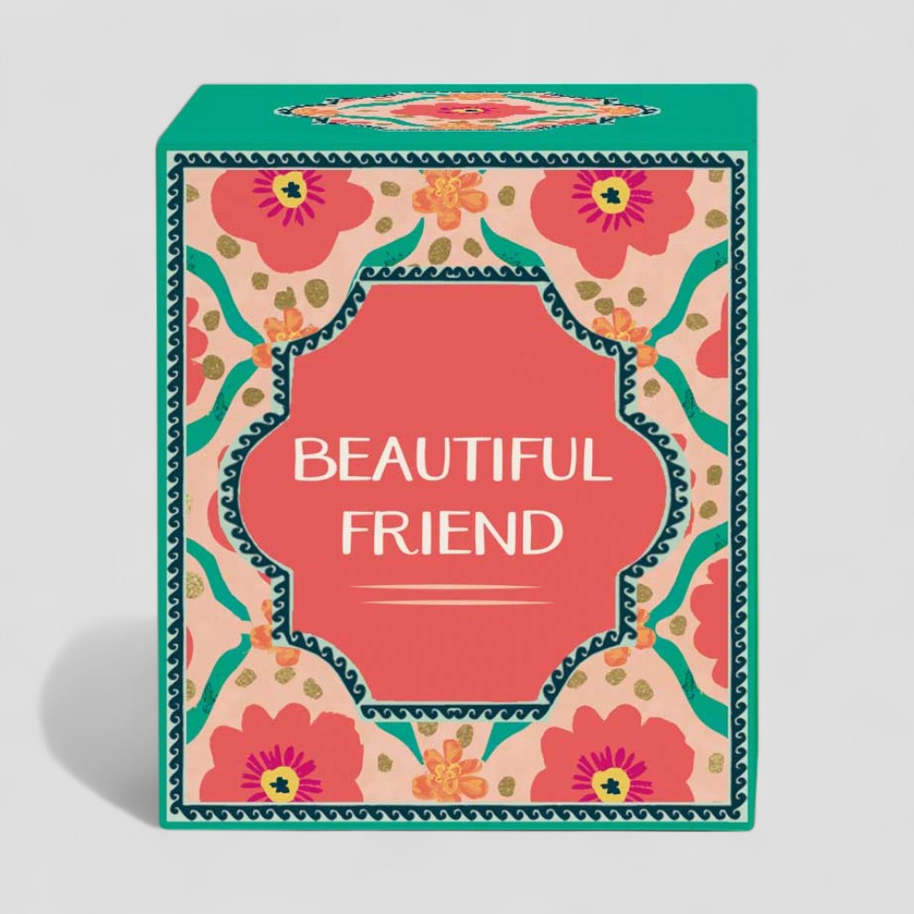 Lit yellow candle in glass with floral patterned beautiful friend box and label
