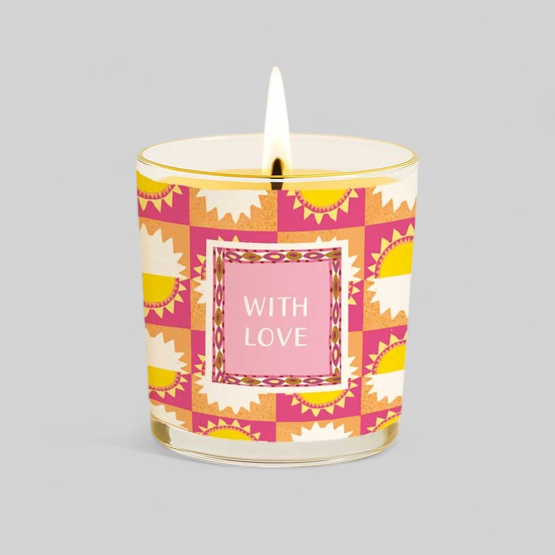 Lit yellow candle in glass with Happy Birthday gift box showing sun design