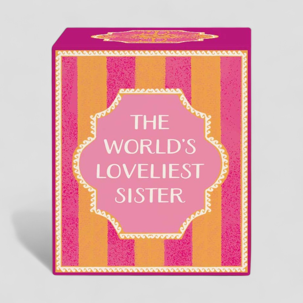 Lit yellow candle and matching box with the words The Worlds Loveliest Sister on plain background