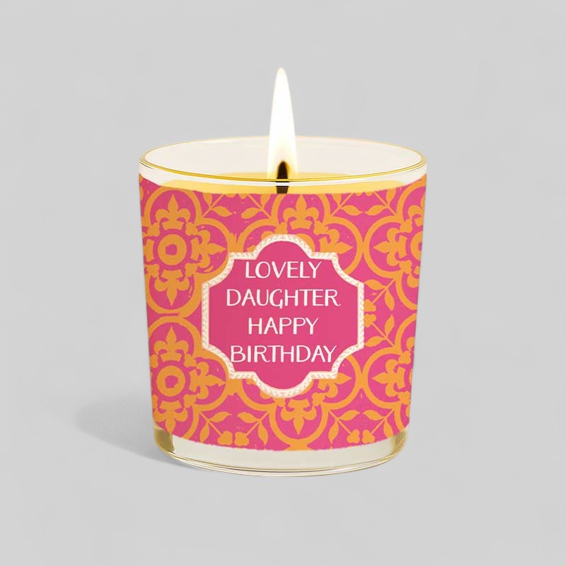Burning yellow candle in glass with pink and gold birthday box for daughter