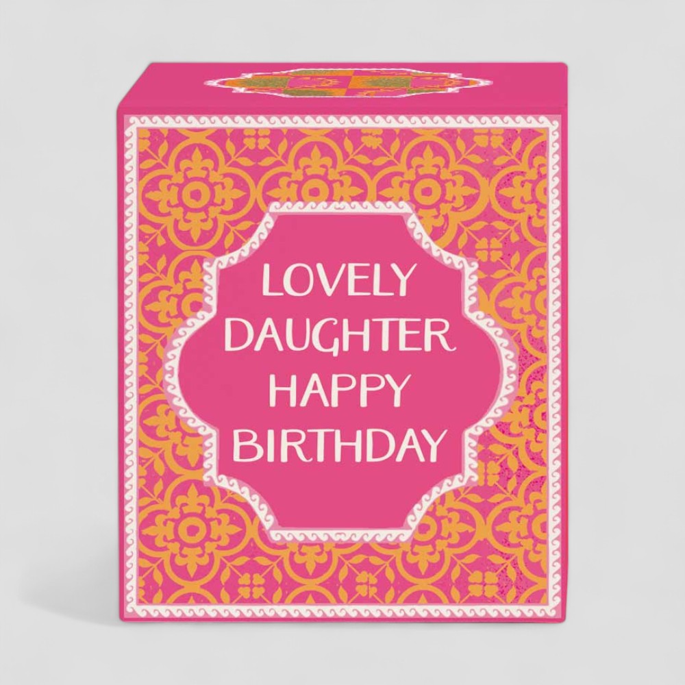 Burning yellow candle in glass with pink and gold birthday box for daughter