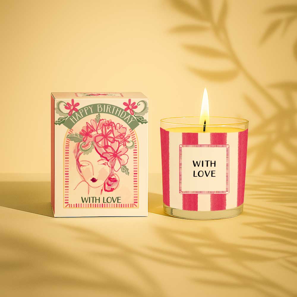 Lit yellow candle in glass with happy birthday with love gift box next to it