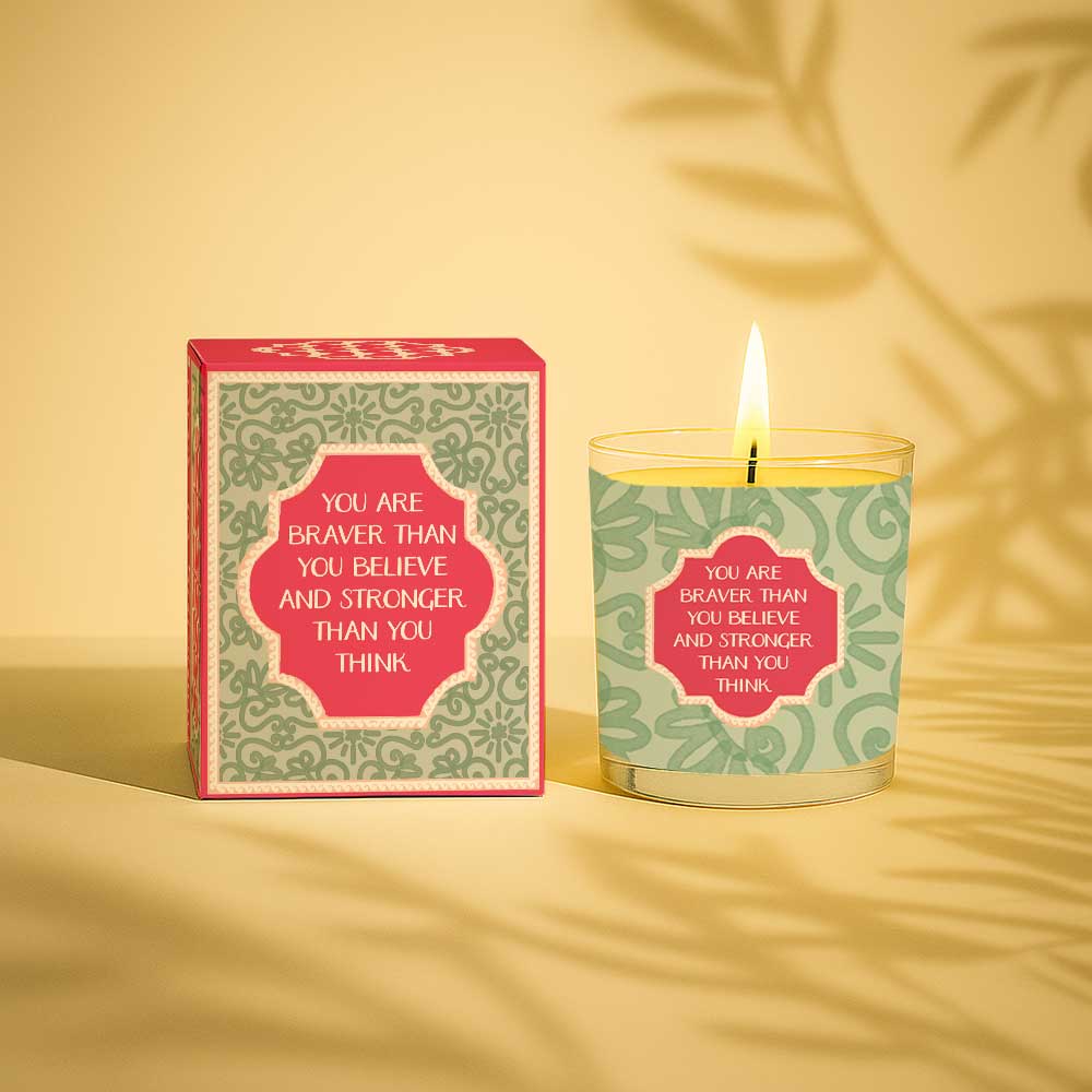 Lit yellow candle with box reading you are braver than you believe and stronger than you think