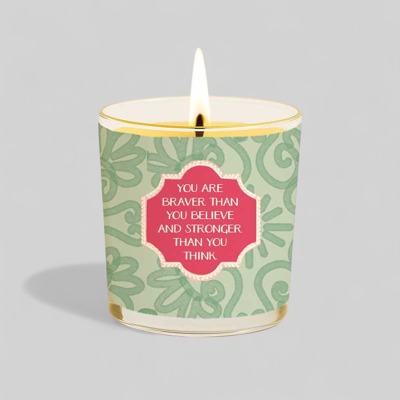 Lit yellow candle with box reading you are braver than you believe and stronger than you think