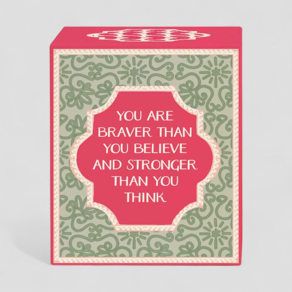 Lit yellow candle with box reading you are braver than you believe and stronger than you think