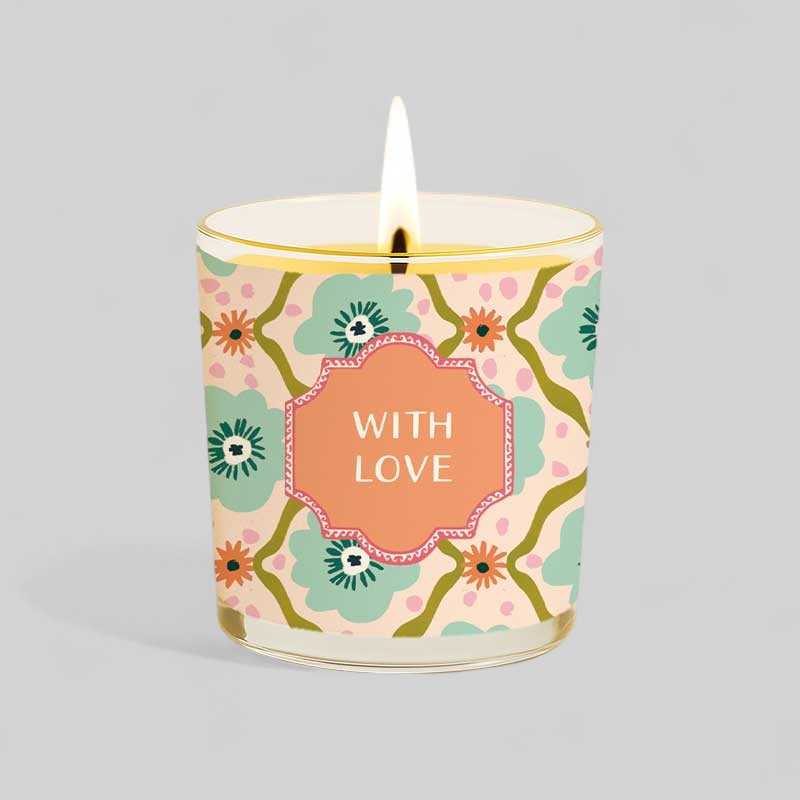 Lit yellow candle next to happy birthday with love gift box with floral design