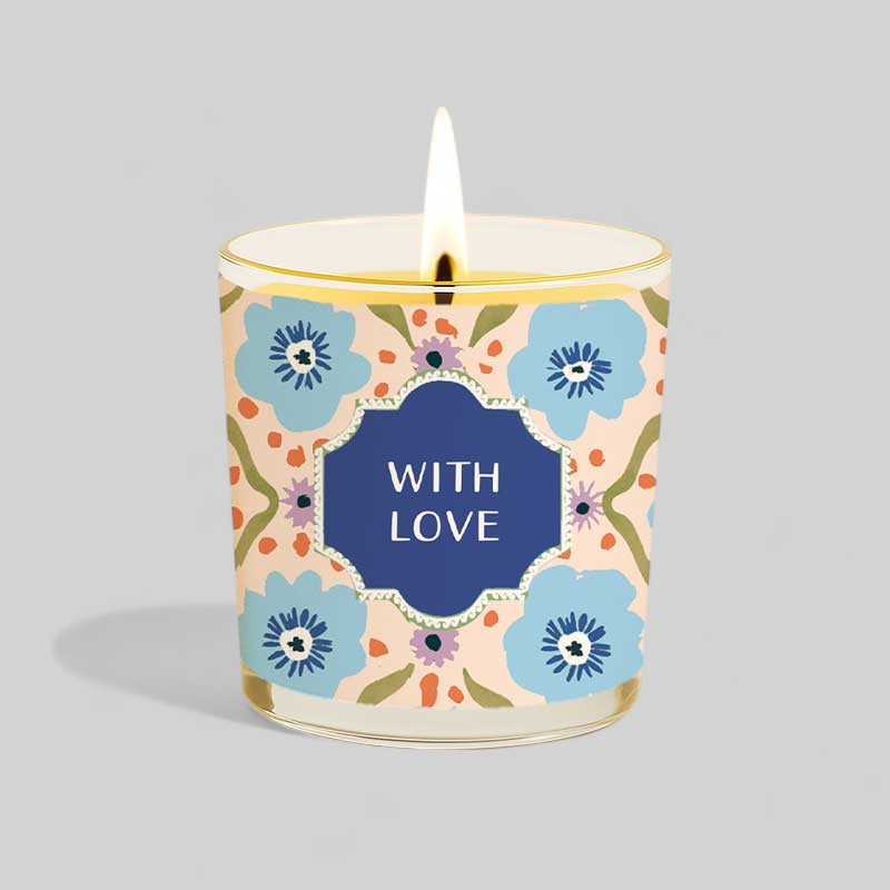 Lit yellow candle and floral birthday gift box with with love label