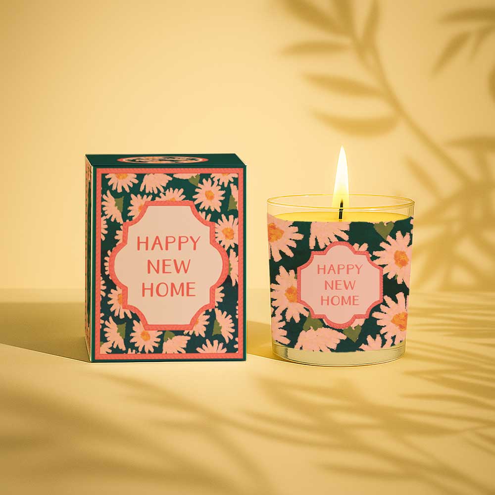Lit yellow candle with floral Happy New Home label and matching gift box
