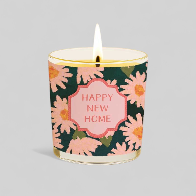 Lit yellow candle with floral Happy New Home label and matching gift box