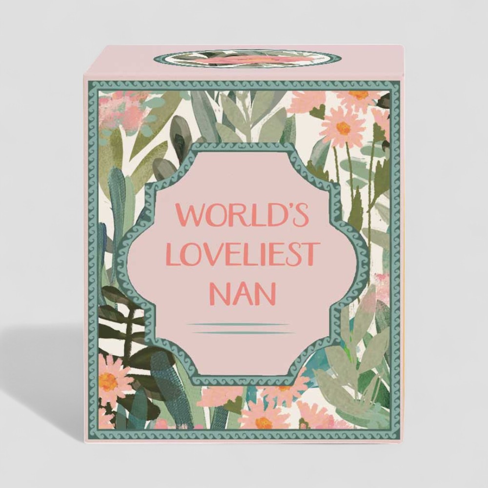 Lit yellow candle beside floral box labelled Worlds Loveliest Nan gift set