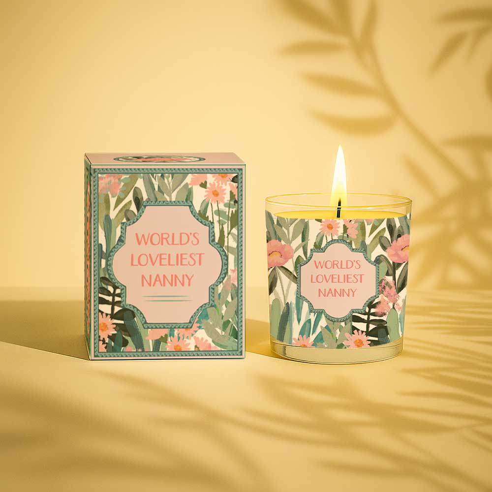Lit yellow candle and box with floral design and text Worlds Loveliest Nanny