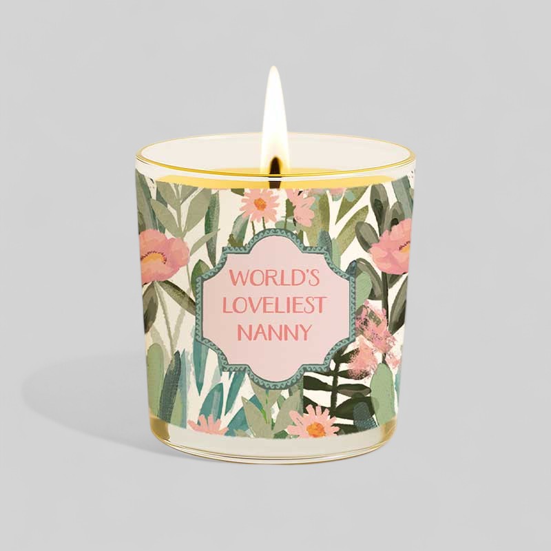 Lit yellow candle and box with floral design and text Worlds Loveliest Nanny