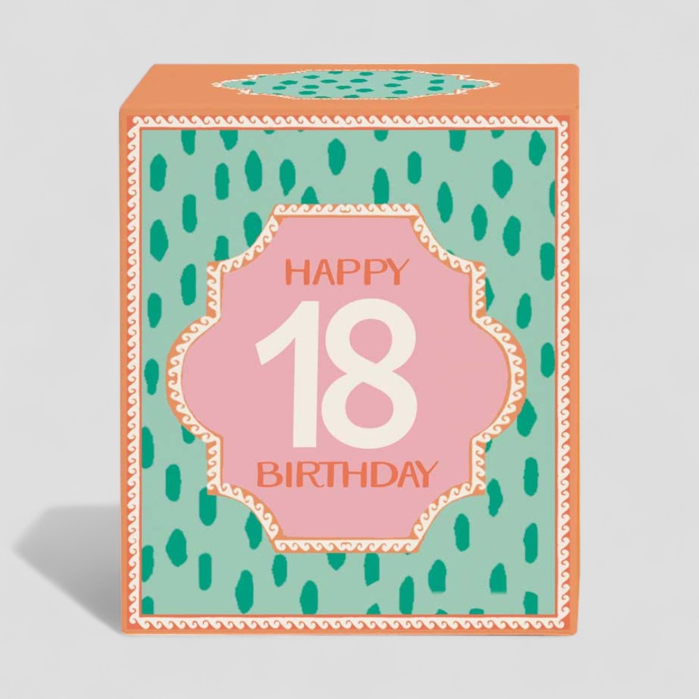 Lit yellow candle and box with Happy 18th Birthday design on pale blue background