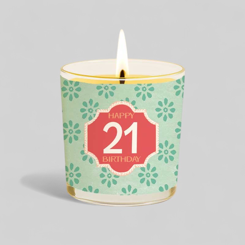 Lit yellow birthday candle in glass with happy 21st birthday design and box