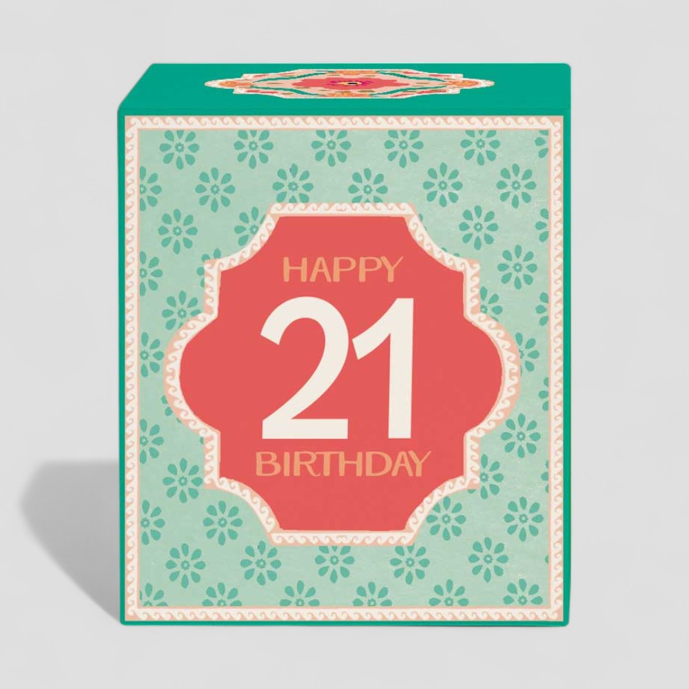 Lit yellow birthday candle in glass with happy 21st birthday design and box