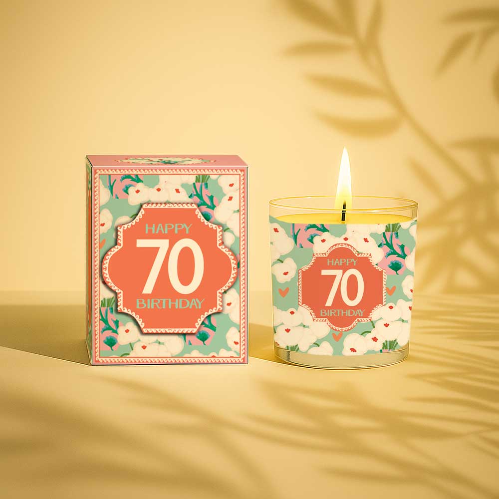 Lit yellow candle with happy 70 birthday label next to matching floral gift box
