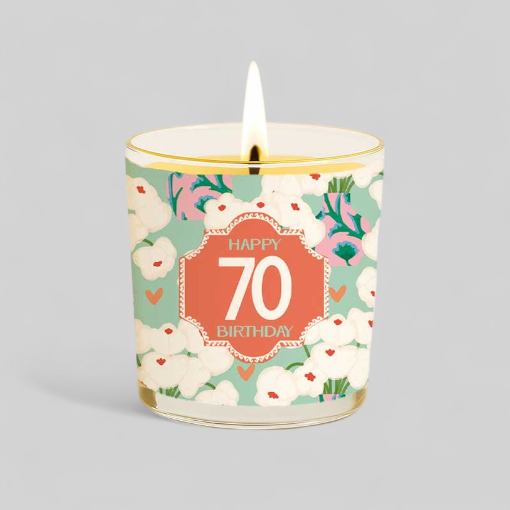 Lit yellow candle with happy 70 birthday label next to matching floral gift box