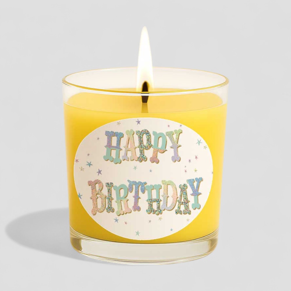 Lit vanilla scented birthday candle next to its box with happy birthday text