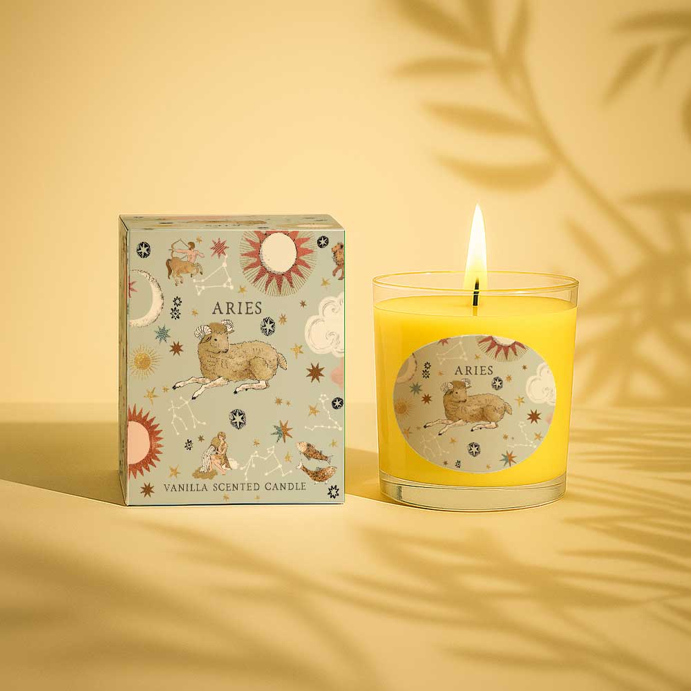 Lit Aries vanilla scented candle next to its decorative box with zodiac design