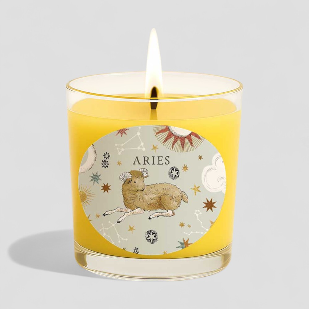 Lit Aries vanilla scented candle next to its decorative box with zodiac design