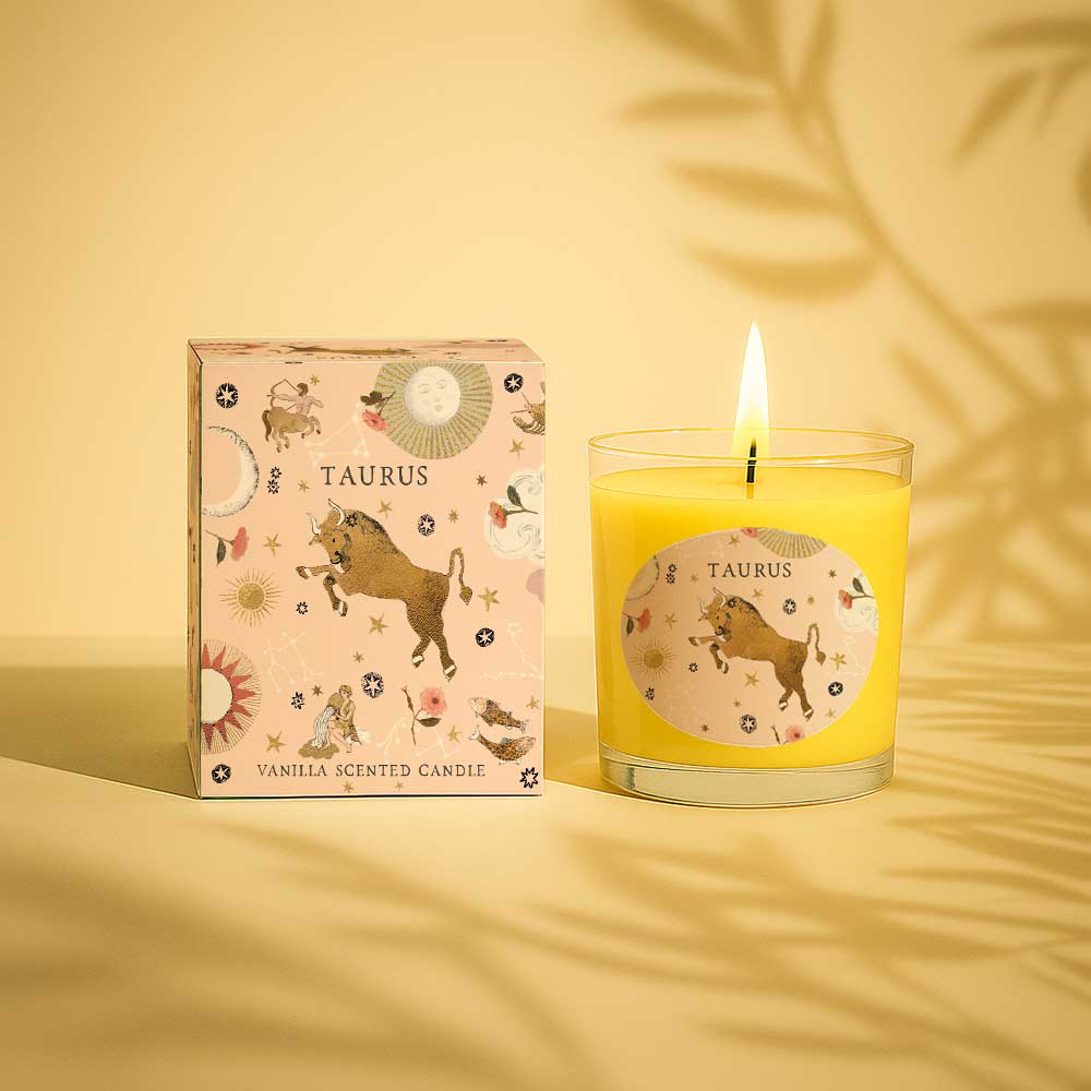Taurus vanilla scented candle with zodiac design and lit wick next to matching box