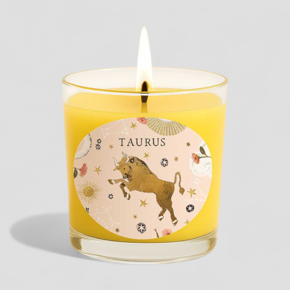 Taurus vanilla scented candle with zodiac design and lit wick next to matching box